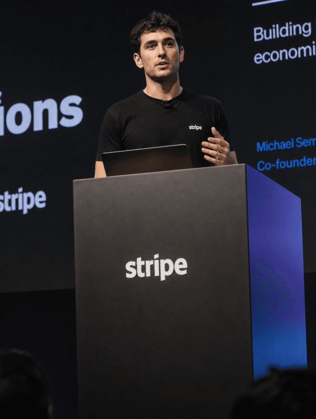 Founder on stage, spotlit, speaking at a podium